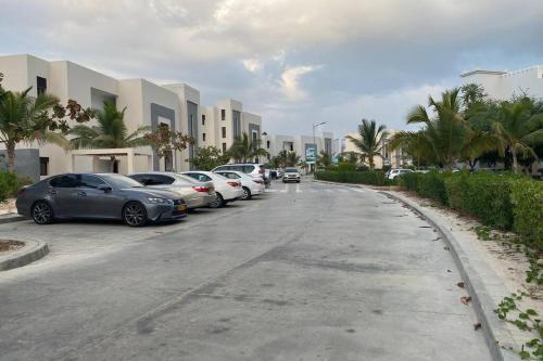 eine Reihe von Autos, die auf einem Parkplatz vor einem Gebäude geparkt sind in der Unterkunft Hawana Salalah lagoon beach apartment in Salalah