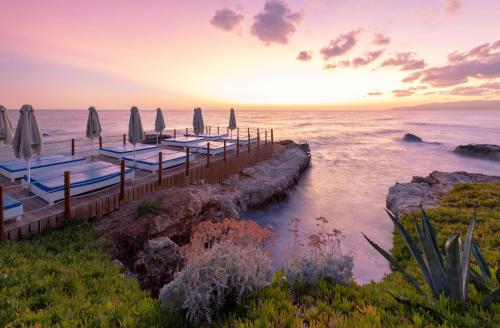 um cais com guarda-sóis e o oceano ao pôr-do-sol em Star Beach Village & Water Park em Hersonissos