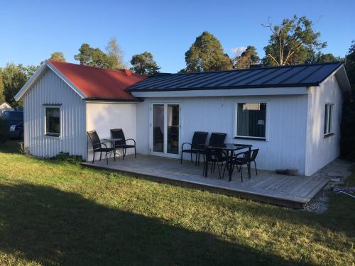 une maison dotée d'une terrasse avec une table et des chaises dans l'établissement Ringbomsvägen Holiday Home, à Ljugarn