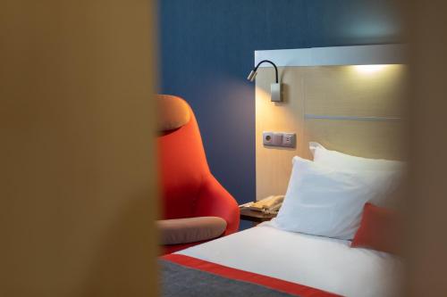 um quarto de hotel com uma cama e uma cadeira vermelha em Holiday Inn Express Porto Exponor, an IHG Hotel em Leça da Palmeira