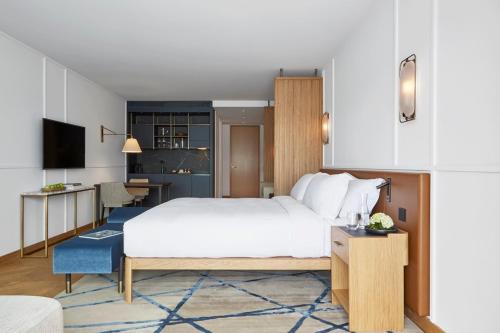 1 dormitorio con 1 cama blanca grande y escritorio en Alex Lake Zürich - Lifestyle hotel and suites, en Thalwil