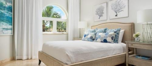 1 dormitorio con 1 cama con almohadas azules y blancas en The Tuscany on Grace Bay, en Grace Bay