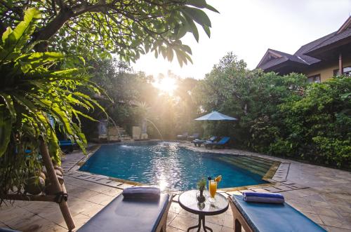 een zwembad met een tafel en stoelen ernaast bij Sri Phala Resort & Villa in Sanur