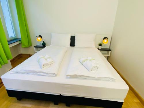 ein weißes Bett mit zwei weißen Hausschuhen drauf in der Unterkunft bestprice Hotel Aachen Hauptbahnhof in Aachen