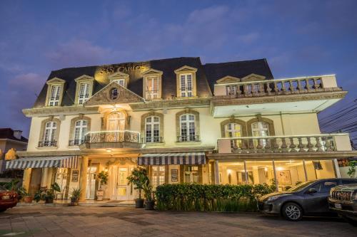 Un grand bâtiment blanc avec balcon se trouve dans une rue. dans l'établissement Hotel San Carlos, à Guatemala