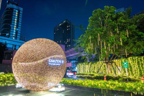 a large gold ball in front of a tree with lights at Carlton Hotel Bangkok Sukhumvit in Bangkok