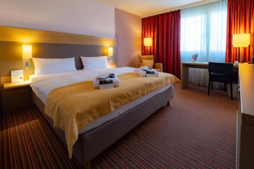 um quarto de hotel com uma cama grande e uma secretária em elaya hotel stuttgart boeblingen em Böblingen