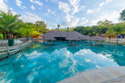 - une piscine bordée de parasols et de palmiers dans l'établissement Rio Quente Resorts - Hotel Luupi, à Rio Quente