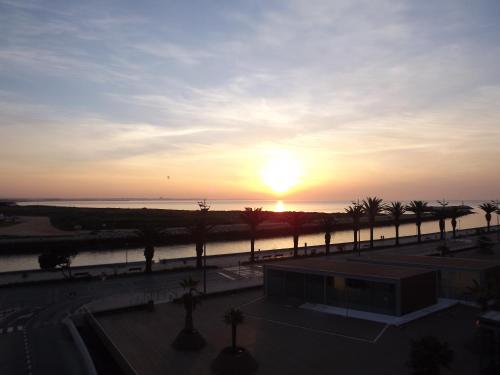 een zonsondergang boven het water met palmbomen en een gebouw bij Hotel Mar Azul in Lagos