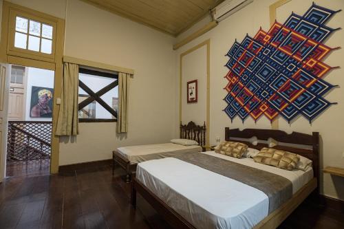 een slaapkamer met 2 bedden en een schilderij aan de muur bij Reviver Hostel in São Luís