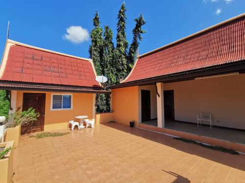 una casa con tetto rosso e patio di Lek Homestay a Si Racha