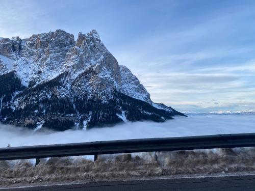 una montaña sobre una capa de niebla junto a una carretera en Appartamento Alpe di Siusi, en Alpe di Siusi