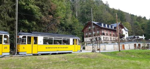 een gele trein is geparkeerd voor een gebouw bij Hotel Forsthaus in Bad Schandau