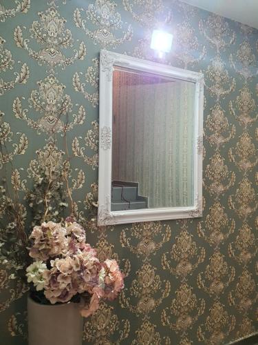 een badkamer met een spiegel en een vaas met bloemen bij Apartments Soleado in Pančevo