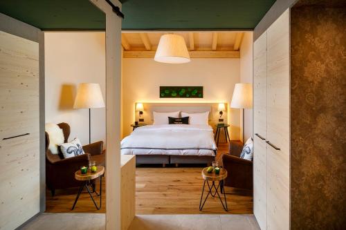 a bedroom with a bed and two chairs at Hotel Sport Klosters in Klosters