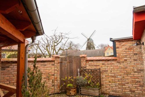 een bakstenen hek met een windmolen op de achtergrond bij Ferienwohnungen Muehlenblick in Röbel