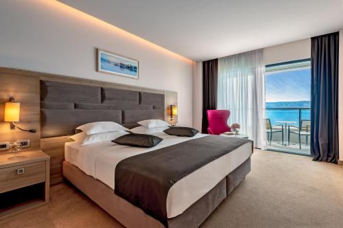 a bedroom with a large bed with a view of the ocean at Hotel Plaža Duće in Duće