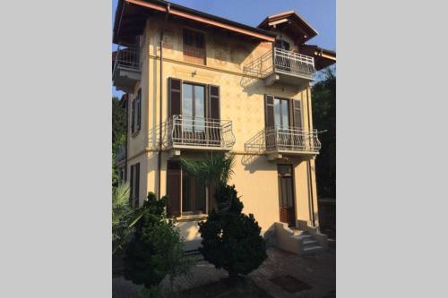 a large yellow building with balconies on it at Villa Peachey, Intero piano con giardino in Stresa