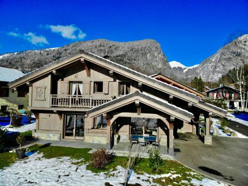 ein großes Holzhaus mit Bergen im Hintergrund in der Unterkunft Chalet Luxe Les Mélèzes in Samoëns