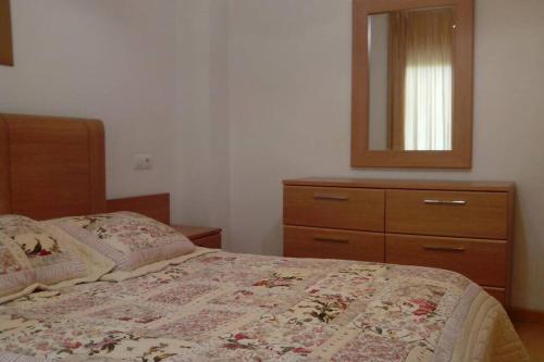 a bedroom with a bed with a dresser and a mirror at Bonito apartamento de 3 hab. con jardín in Roses