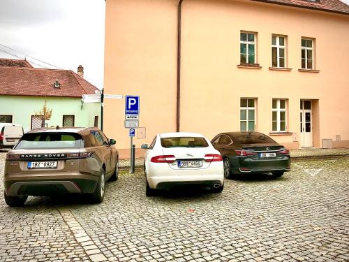 três carros estacionados num parque de estacionamento ao lado de um edifício em Boutique Apartments U Rolanda, Mikulášské náměstí em Znojmo