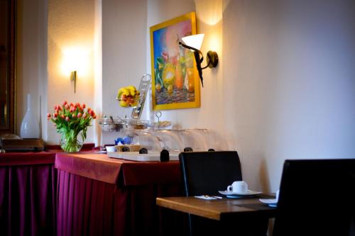 - une table dans une chambre d'hôtel avec une table et des fleurs dans l'établissement Hotel am Landeshaus, à Wiesbaden