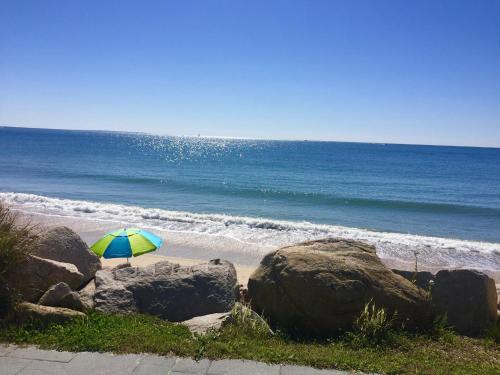 plaża z parasolem, skałami i oceanem w obiekcie Pleasant View Inn w mieście Westerly