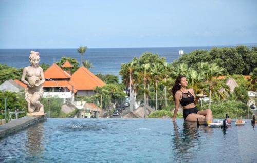 Eine Frau, die im Wasser neben einer Statue sitzt. in der Unterkunft Kayangan Boutique Hotel in Sanur