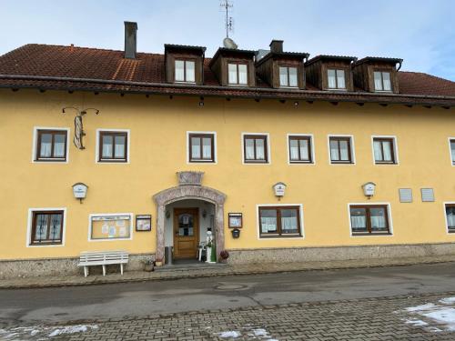 um edifício amarelo com um banco à frente em Gasthof zum Kirchenwirt em Kirchdorf am Inn