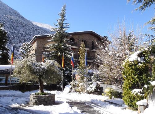 ein Gebäude im Schnee mit Flaggen davor in der Unterkunft Hotel Guillem & Spa in Encamp