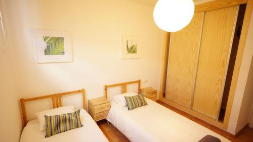 two beds in a small room with a lamp at Surfers Retreat in Corralejo