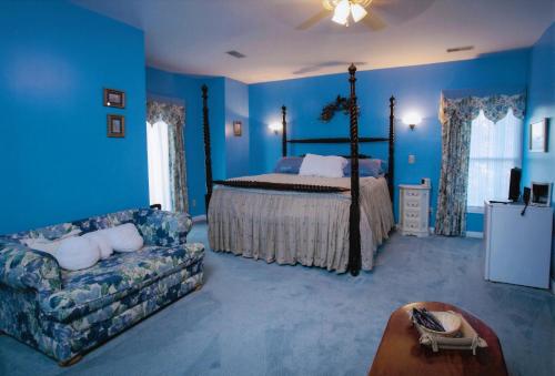 Dormitorio azul con cama y sofá en Rabbit Creek Bed & Breakfast, en Versailles