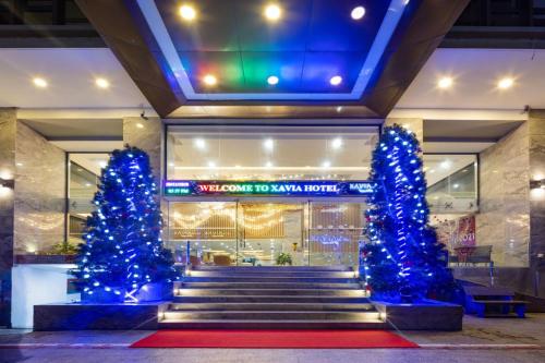 dos árboles de Navidad delante de un edificio con luces azules en Xavia Hotel, en Nha Trang