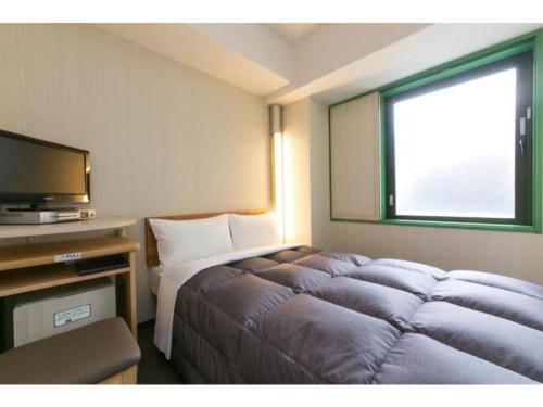 een hotelkamer met een bed en een televisie bij R&B Hotel Kumagaya Ekimae - Vacation STAY 14849v in Kumagaya