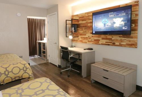 a bedroom with a desk and a tv on a wall at Baymont by Wyndham Gatlinburg On The River in Gatlinburg