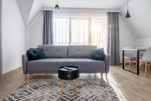 uma sala de estar com um sofá e uma mesa em Tatra Apartments z zewnętrznym jacuzzi em Biały Dunajec