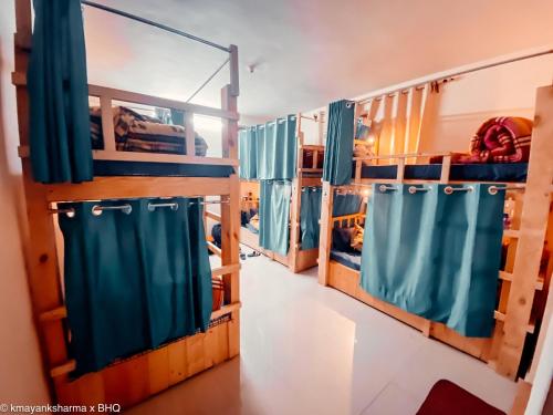 a room with bunk beds with blue curtains at Backpackers Headquarter Manali in Manāli