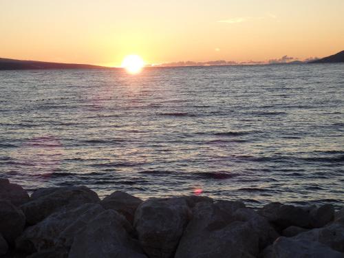 a sunset over the water with rocks at Apartmani Stipan in Brela