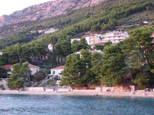 a group of houses on a hill next to a body of water at Apartmani Stipan in Brela