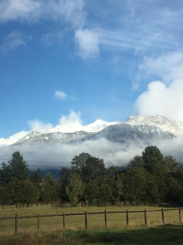 vistas a las montañas cubiertas de nieve con árboles y una valla en Cabañas Río del Este SPA, en Puerto Varas