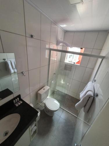 a white bathroom with a toilet and a sink at Hotel Carmelo in São José dos Pinhais