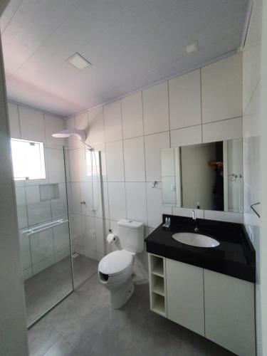 a bathroom with a toilet and a sink and a shower at Hotel Carmelo in São José dos Pinhais