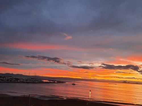 a sunset over a body of water with a beach at Apartamentos Ferrán Paqui in Roses