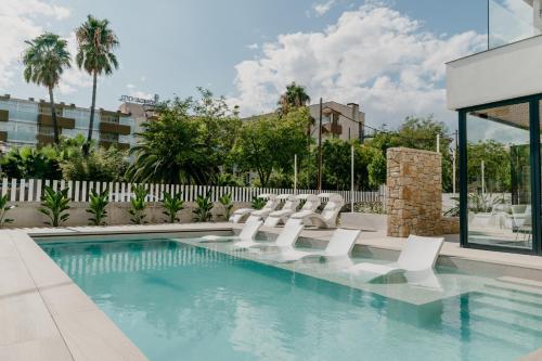 une piscine avec des chaises longues blanches et une piscine dans l'établissement Instants Boutique Hotel - Adults Only, à Cambrils