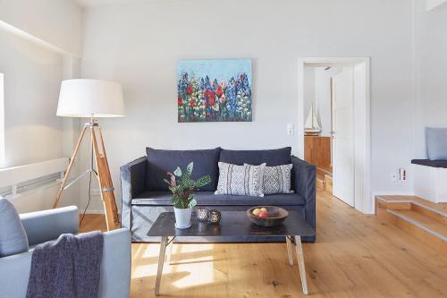 ein Wohnzimmer mit einem blauen Sofa und einem Tisch in der Unterkunft Pierspeicher Boardinghouse in Kappeln