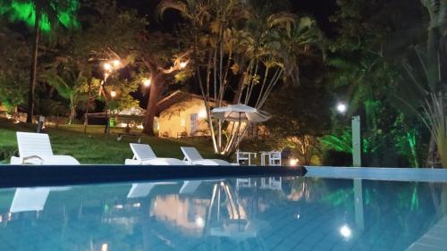 - une piscine de nuit avec des chaises et un parasol dans l'établissement Pousada Rio da Vila, à Porto Seguro