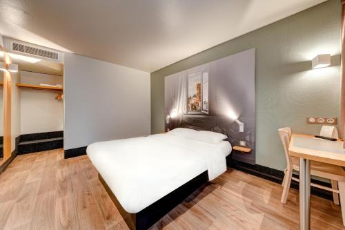 a bedroom with a white bed and a desk at B&B HOTEL Louveciennes in Louveciennes