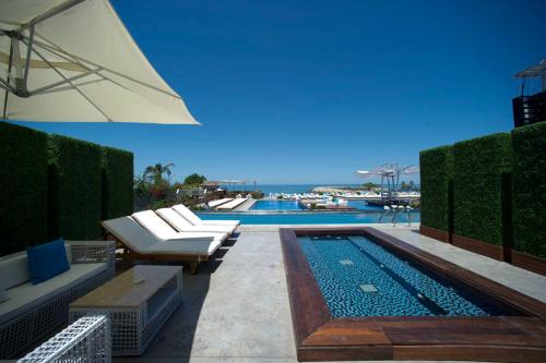 - une piscine avec des chaises longues et un parasol dans l'établissement Veer Luxury Boutique Hotel & Beach Club, à Jounieh