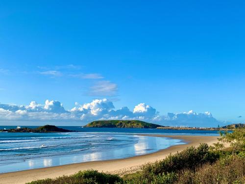 a beach with waves and islands in the water at Surf Beach Motel Coffs in Coffs Harbour