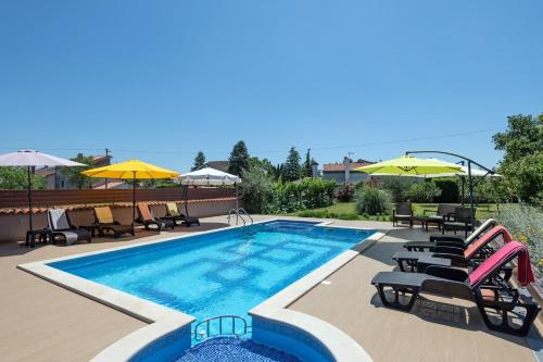 - une piscine bordée de chaises et de parasols dans l'établissement Apartments Brioni Colors, à Pula